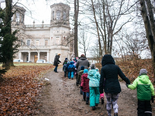 Kinder laufen hintereinander zu einem Schloss.